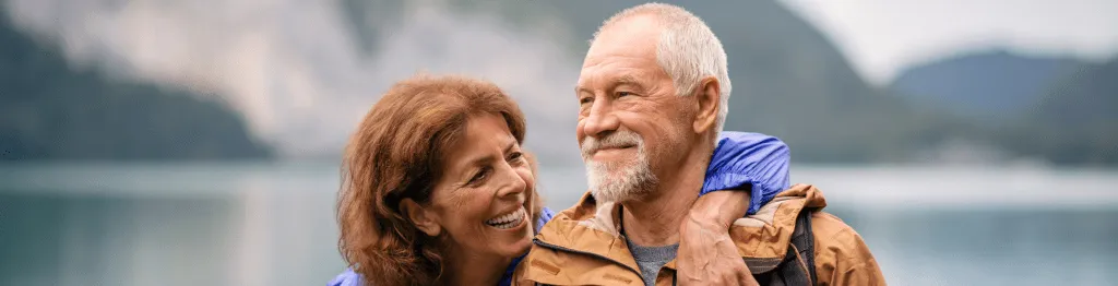 Senior pensioner couple hiking by lake in nature, enjoying the results of sustainable retirement planning in Perth.